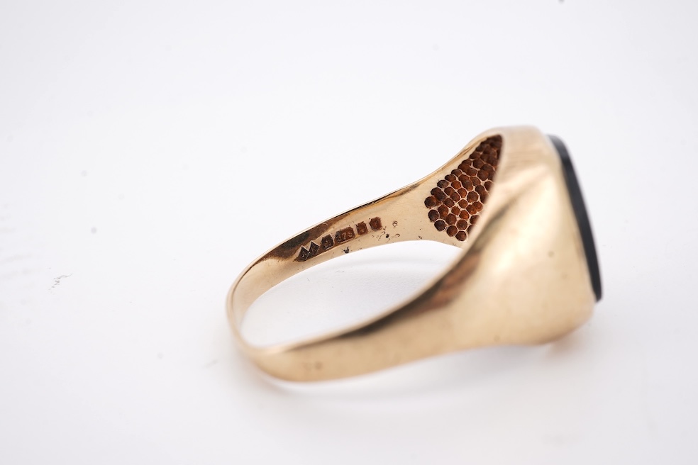 A 1980's 9ct gold tie clip, 39mm and a similar 9ct gold and black onyx set signet ring, gross weight 10 grams.